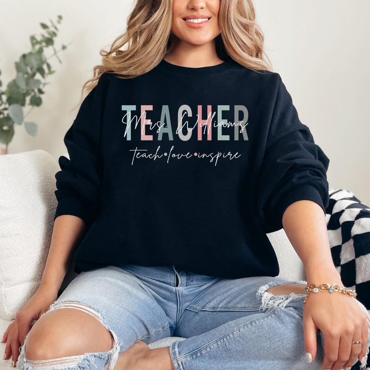 Woman wearing custom Teach Love Inspire crewneck sweatshirt, personalized teacher appreciation gift idea.