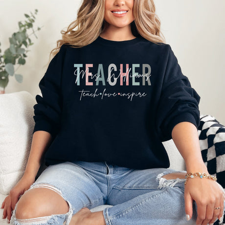 Woman wearing custom Teach Love Inspire crewneck sweatshirt, personalized teacher appreciation gift idea.