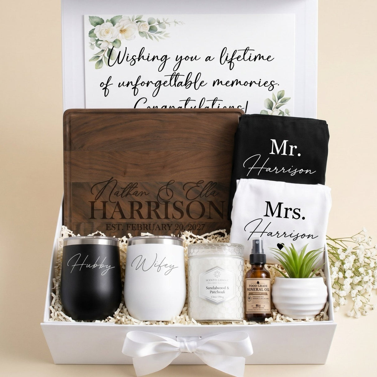 Custom wedding gift for bride and groom. This gift set includes a custom engraved cutting board, hubby and wifey wine tumblers, scented candle, his and her aprons and plant in custom gift box with personalized message.
