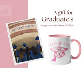 College graduates celebrating next to a pink class of 2024 graduation coffee mug. All SKUs. 