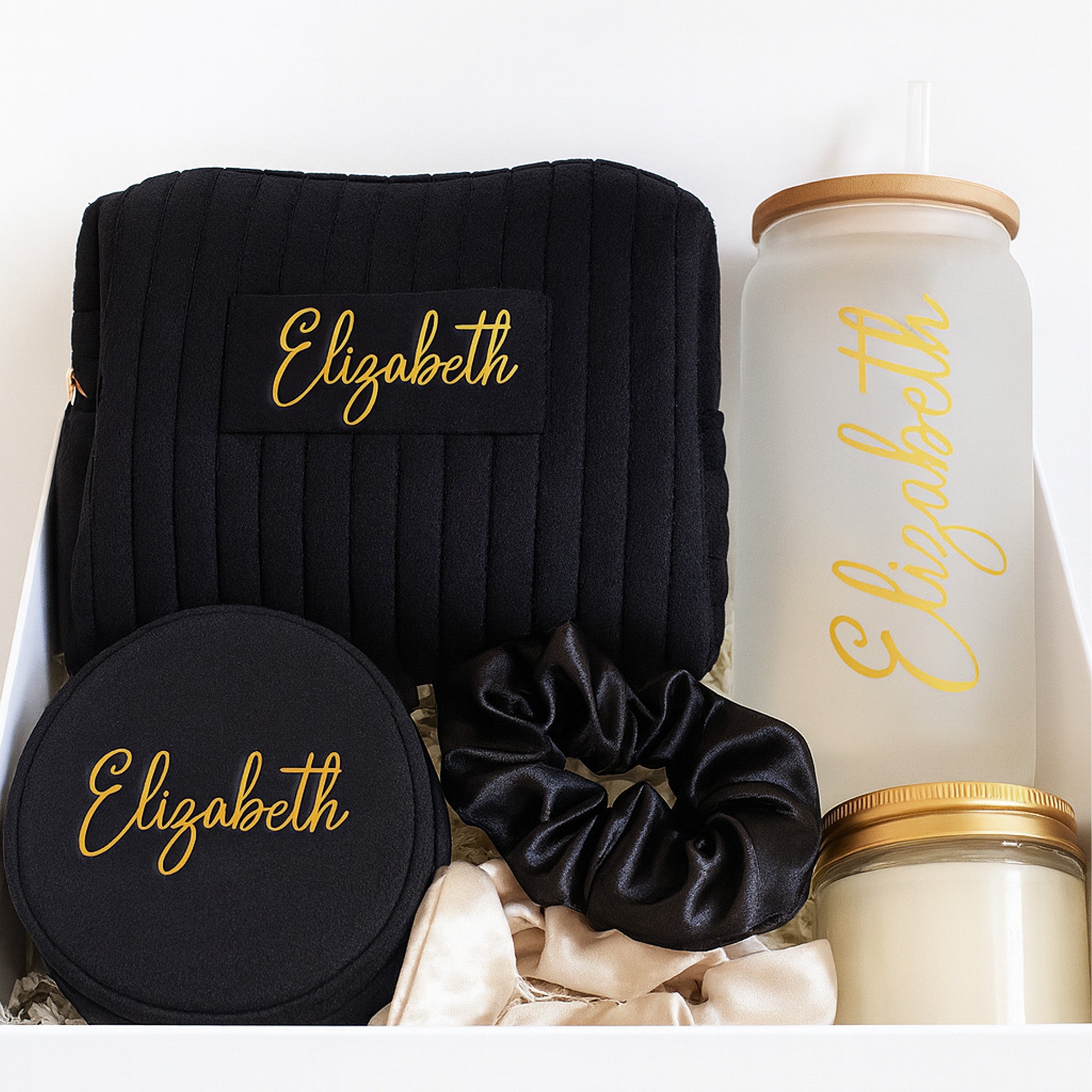 Black and gold theme personalized bridesmaid gifts with a cute black velvet makeup bag, a frosted glass can, a black velvet jewelry box, 2 scrunchies and a gold lid candle. The perfect way to ask will you be my bridesmaid?