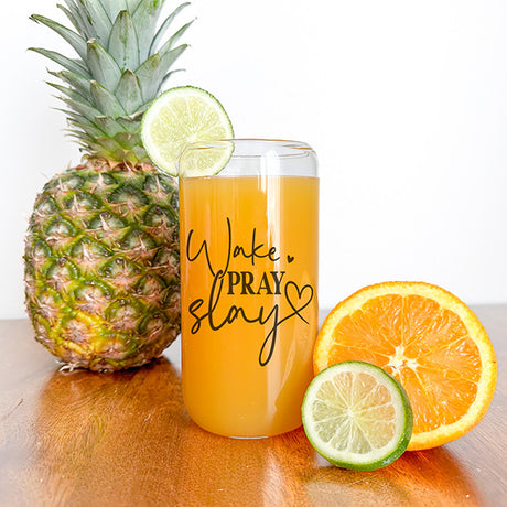 Clear glass can with fruit juice. This tumbler features the words Wake, Pray, Slay.