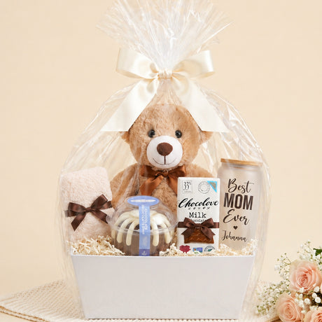 Gift basket with chocolate bundt cake, chocolate bar, teddy bear, fuzzy socks and personalized glasscan with the words Best Mom Ever and her name. Great gift for mothers day, birthdays and just because.