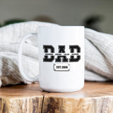 Custom dad mug with children’s names and year in varsity lettering, perfect personalized Father’s Day gift from kids or spouse.