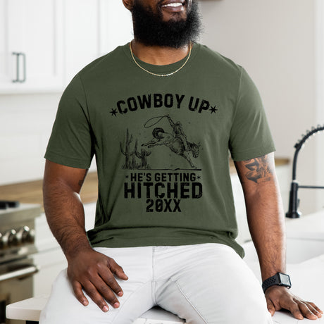Custom he's getting Cowboy Up t-shirt featuring bold western-theme, perfect personalized bachelor party outfit for wedding crews.