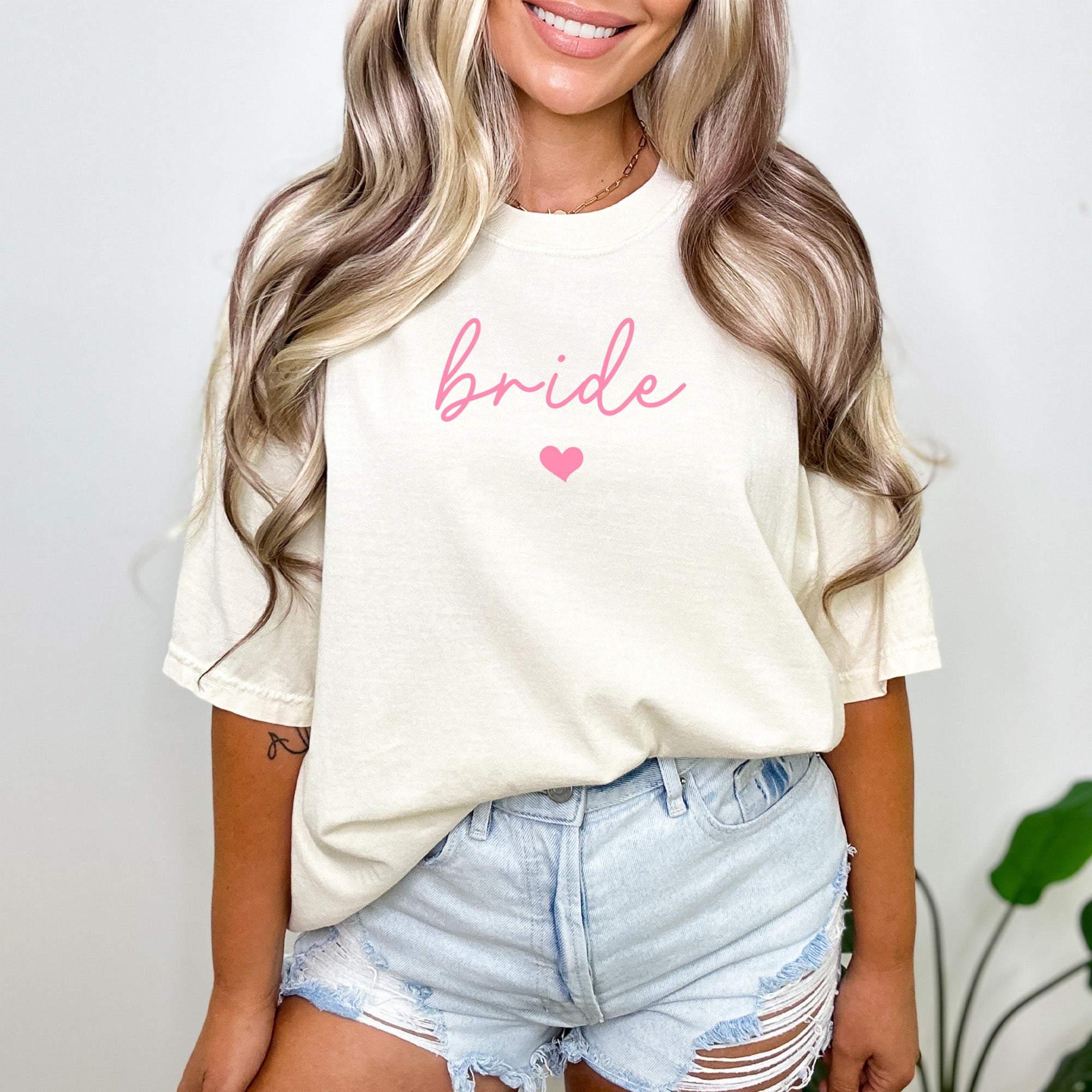 Bride wearing a custom Comfort Colors sweatshirt with Bride text, ideal for bachelorette parties or morning-of wedding photos. Cute and simple bride to be gift.