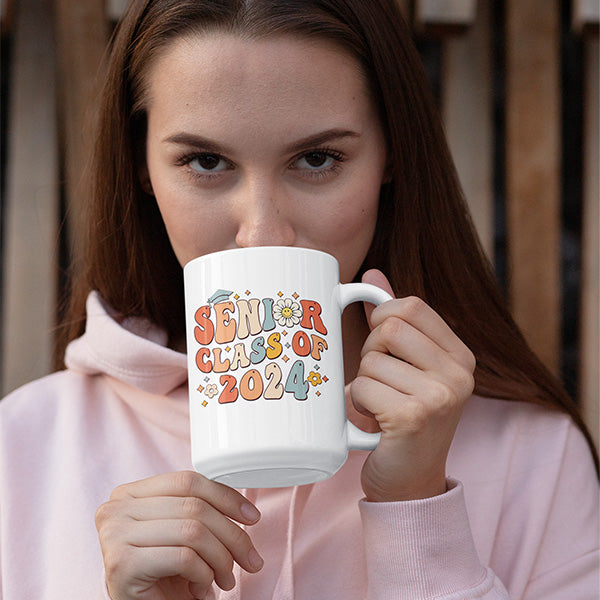 Woman drinking coffee from a 15oz class of 2024 senior graduation cofee mug. All SKUs.