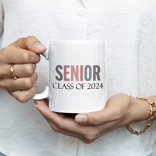 Woman holding senior class of 2024 coffee mug to commemorate the class of 2024. All SKUs.