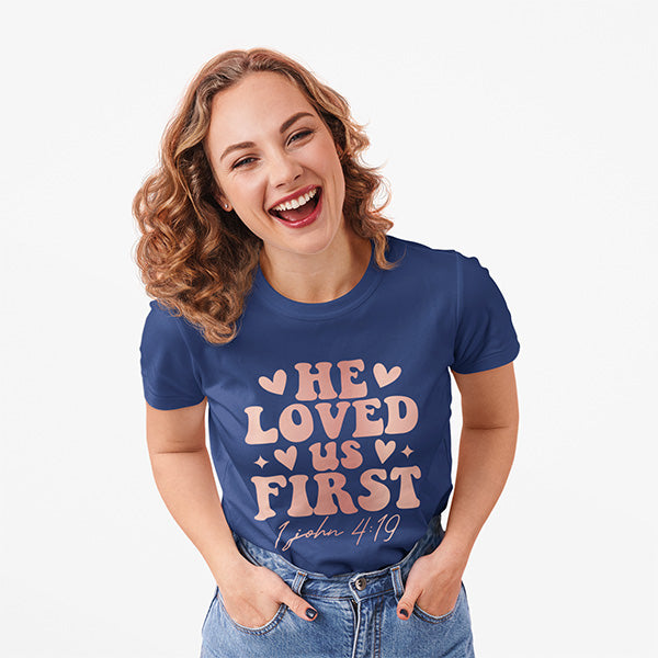 A religious shirt for Christian with the text from 1 John 4 19, He Loved Us First.  Available in a various colors including black, white, blue, green, red, gray, purple, pink and more. all SKUs